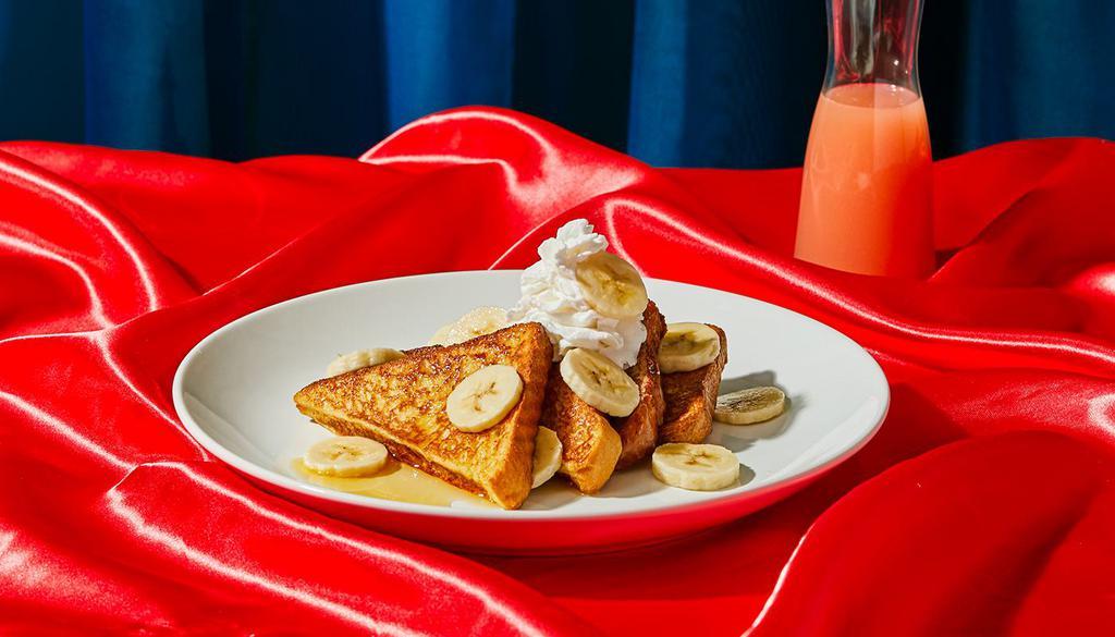 Banana French Toast · Four slices of thick, egg-washed cinnamon bread topped with fresh bananas, and served with maple syrup and powdered sugar.