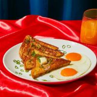 Savory French Toast · Two slices of thick, egg-washed cinnamon bread topped two fried eggs and served with syrup a...