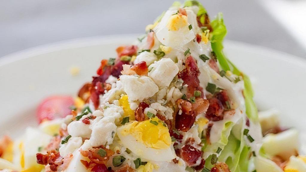 Wedge Salad · crisp wedge salad top with bacon crumbles, walnut pesto,tomatoes,iceberg,egg,red onion with creamy blue cheese dressing.