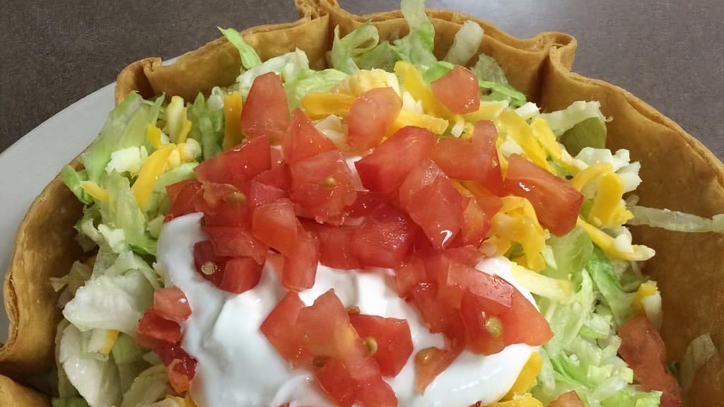 Taco Salad · Crisp flour tortilla shell filled with your meat choice and lettuce, topped with cheese, sour cream, and tomato.