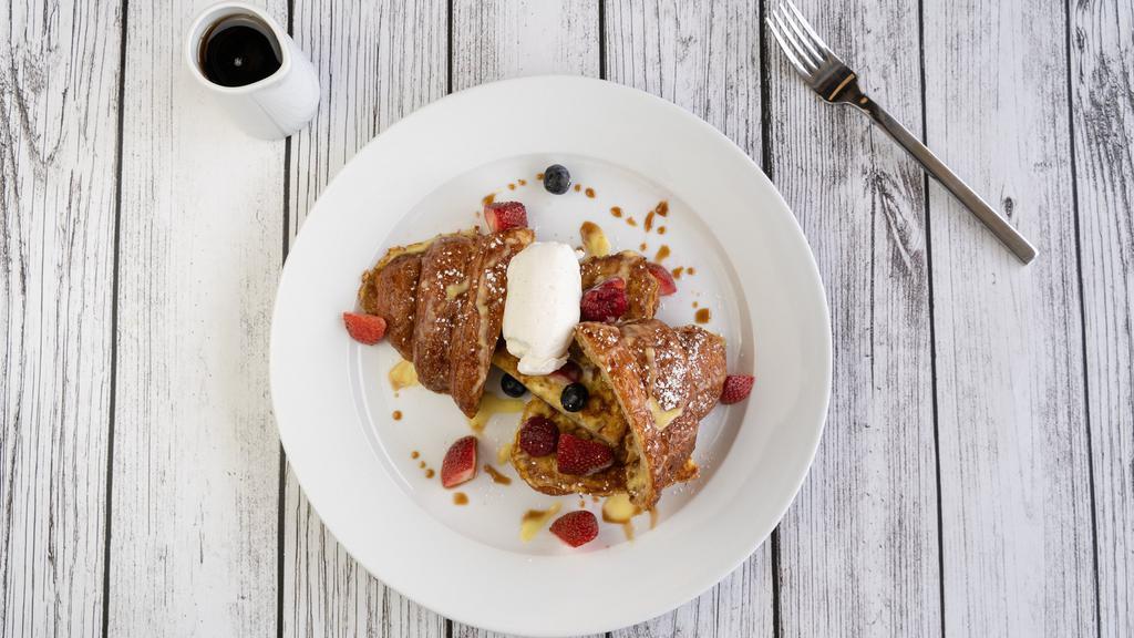 Croissant French Toast · Vegetarian. Fresh baked butter croissant soaked in eggs and milk, cooked until golden brown and drizzled with a vanilla cream sauce, pomegranate molasses, topped with fresh whipped cream and berries.