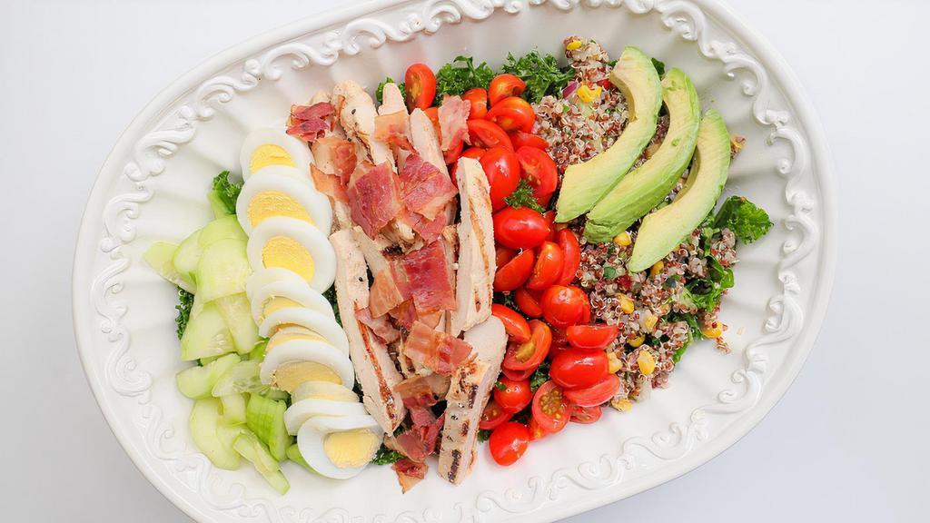 California Cobb Bowl · Natural Chicken Breast, Avocado, Bacon, Gorgonzola Cheese, Hardboiled Egg, Cucumber, Tomato, and Red Onions served on a bed of Organic Kale and Organic Quinoa, with Balsamic Vinaigrette on the side. Our quinoa is mixed with red bell pepper, cucumber, corn, and parsley.