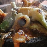 Molcajete Mix · Steak chicken and shrimp cocked with molcajete sauce serve in a stone bowl with green onions...