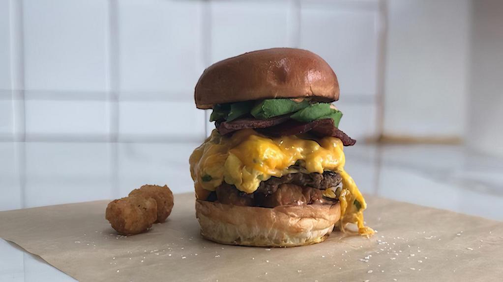 Broke Millionaire · Scrambled eggs, chives, caramelized onions, cheddar cheese, smashed tots, house made pork sausage patty, bacon, avocado and our signature Bandit aioli.
