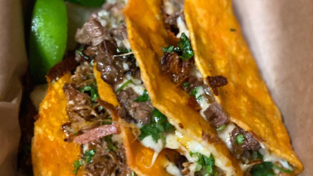 Quesabirria · Corn tortilla dipped in our house chili oil, filled with a melted blend of Mexican cheeses, braised beef, fresh onions, cilantro, and salsa verde then grilled until slightly crispy. We recommend adding a side of consome to dip it in.