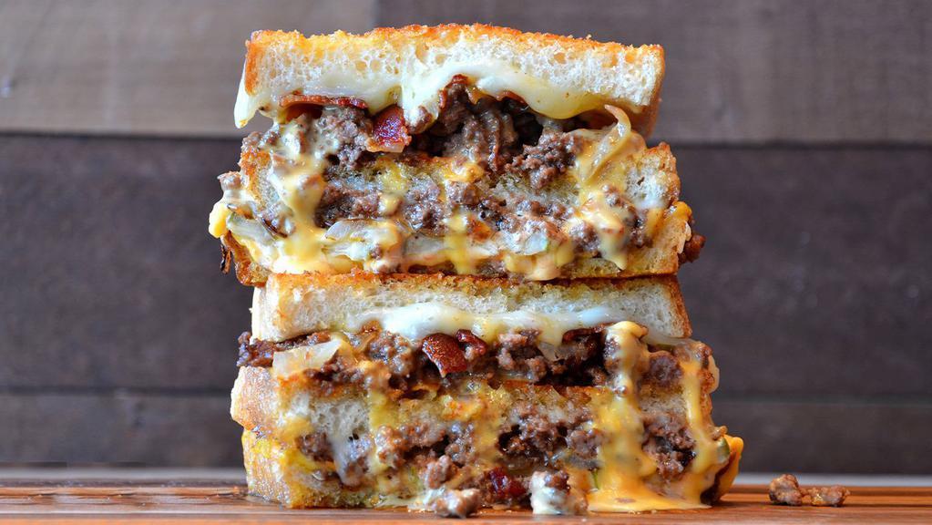 Double Burger With Bacon Grilled Cheese  · Crumbled burger meat topped with bacon, American and provolone cheese, caramelized onions, pickles and 1000 island dressing on Parmesan sourdough.