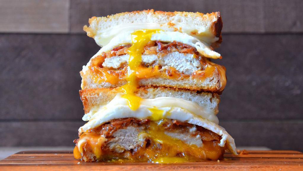 Dilemma Grilled Cheese · Hand-breaded chicken breast topped with a fried egg, crispy bacon, provolone and cheddar cheese on artisan bread with miso maple butter.