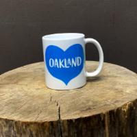 Heart Oakland Mug  · 11 oz. white ceramic mug with Blue heart and white letters spelling OAKLAND