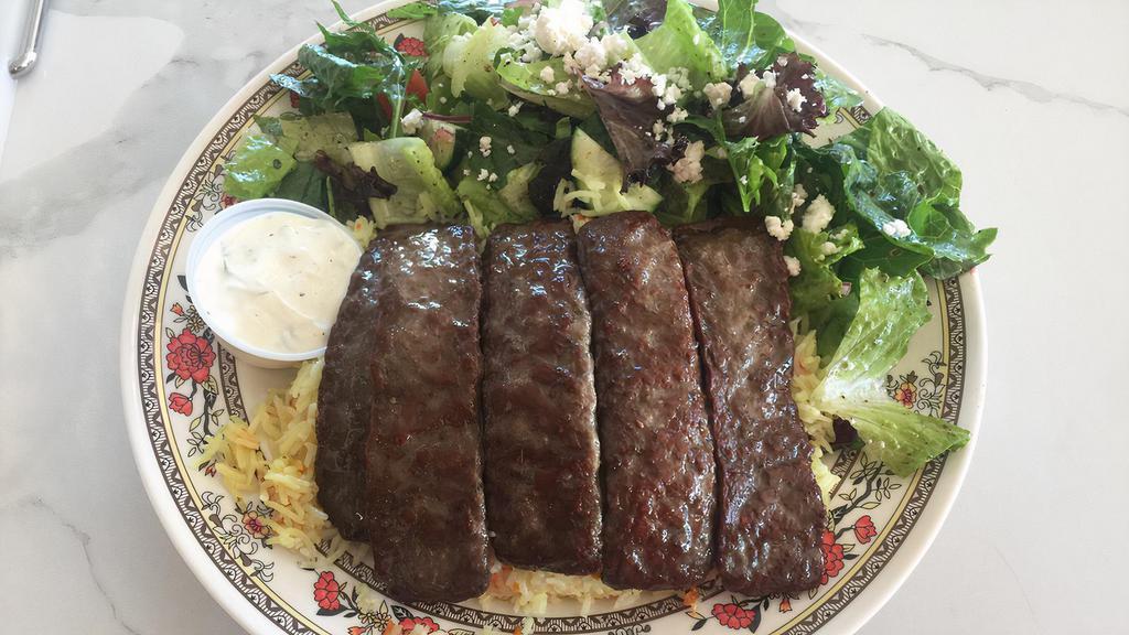 Gyros Plate · Five strips of grilled beef and lamb gyros served with rice pilaf, Greek salad, and tzatziki.