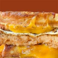 Chicken & Waffle Sandwich · Fried egg, crispy fried chicken, cheddar, and spicy maple syrup, served on a bacon waffle bun.
