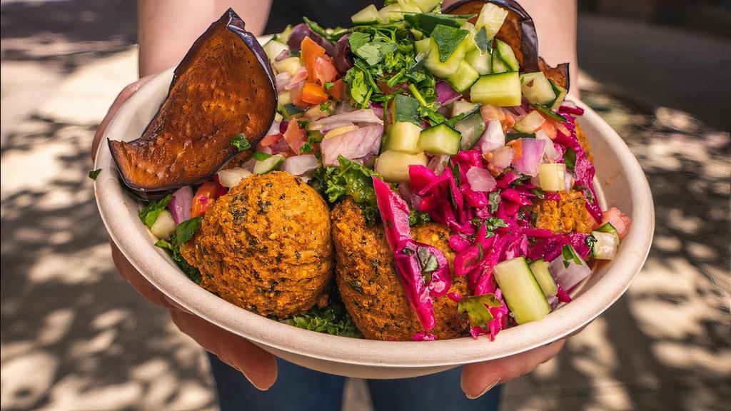 Plant Powered Protein Bowl · Protein packed bowl made with couscous, garbanzo, spinach, eggplant hummus, fried eggplants, kalamata olives, cucumbers, white cabbage, herb mix, garlic jalapeño tahini.