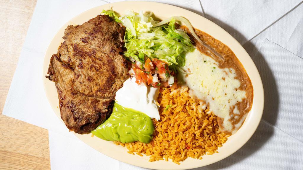 Carne Asada Plate · Two pieces of Grilled Carne Asada served with rice, refried beans topped with cheese, pico de gallo salsa, sour cream, guacamole, lettuce with option of corn or flour tortillas.