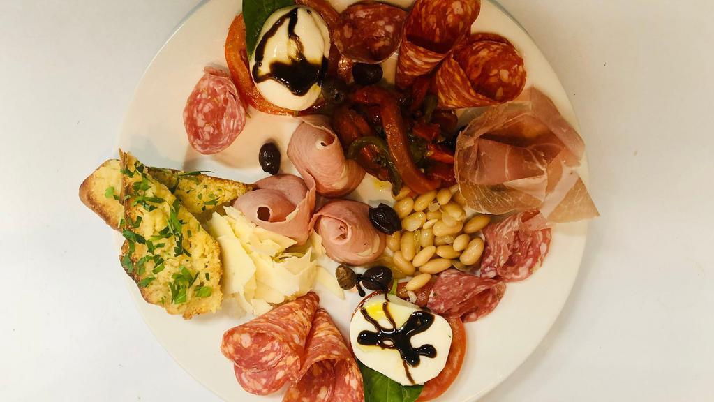 Antipasto Misto · A cold dish sampler of Mortadella with pistachio, spicy Calabrese salami, prosciutto, roasted bell peppers, and Caprese salad.