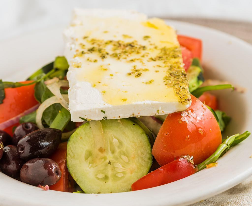 Greek Village Salad · Tossed tomatoes, cucumbers, arugula, bell peppers, red onions, and kalamata olives with greek house dressing. Topped with a thick slice of feta cheese.