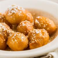 Lukamathes · Greek honey puff donuts coated in a honey sugar syrup with crushed walnuts and powdered sugar.