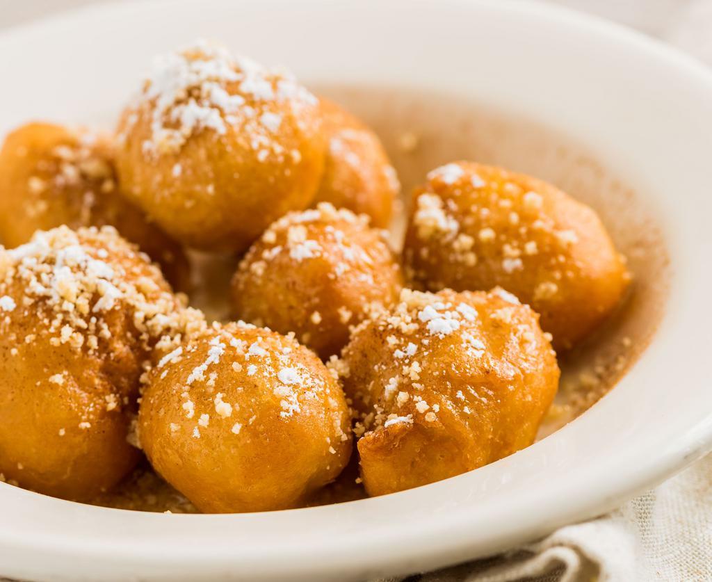 Lukamathes · Greek honey puff donuts coated in a honey sugar syrup with crushed walnuts and powdered sugar.