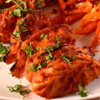 Tandoori Chicken Momo · Fresh tandoori based momo cooked in tandoori sauce and bedded with chef's special noodles.