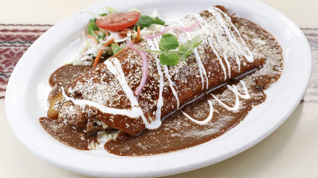 Joe Strummer · Flour tortilla filled with black beans, pork, plantains, rice & covered in mole sauce. Sprinkled with ono cheese & a dab of sour cream.