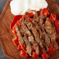 Iskender Kabob Plate · Iskender kabob is lamb shawarma topped with hot tomato sauce butter over pieces of pita brea...