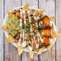 Super Nachos · Choice of meat, cheese, refried beans, sour cream, guacamole, jalapeños, and cilantro garnish.