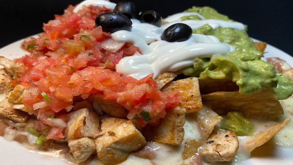 Super Nachos · Your meat choice (steak, pork or grilled chicken) over homemade corn chips, with Monterey jack melted cheese, refried beans, salsa fresca, sour cream, guacamole, olives & meat.