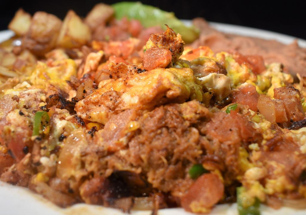 *Machaca Plate · Scrambled eggs, serranos, tomatoes, onions and carnitas served with refried beans, grilled potatoes, salsa fresca & avocado slice. Your choice of corn or flour tortilla.