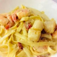 Fettuccine Alla Portofino · Flat pasta in a creamy garlic sauce, sundried tomato, white wine, shrimp and scallops.