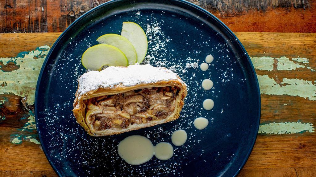 Apple Strudel with Vanilla Sauce · Flaky, buttery apple strudel with rum soaked raisins, almonds. Served with Vanilla Sauce