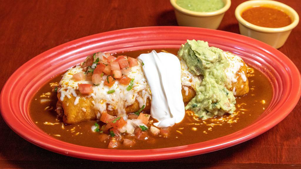 Burrito Mojado · Stuffed with your choice of meat, rice, beans, pico de gallo, topped with enchilada sauce, melted cheese, guacamole and sour cream