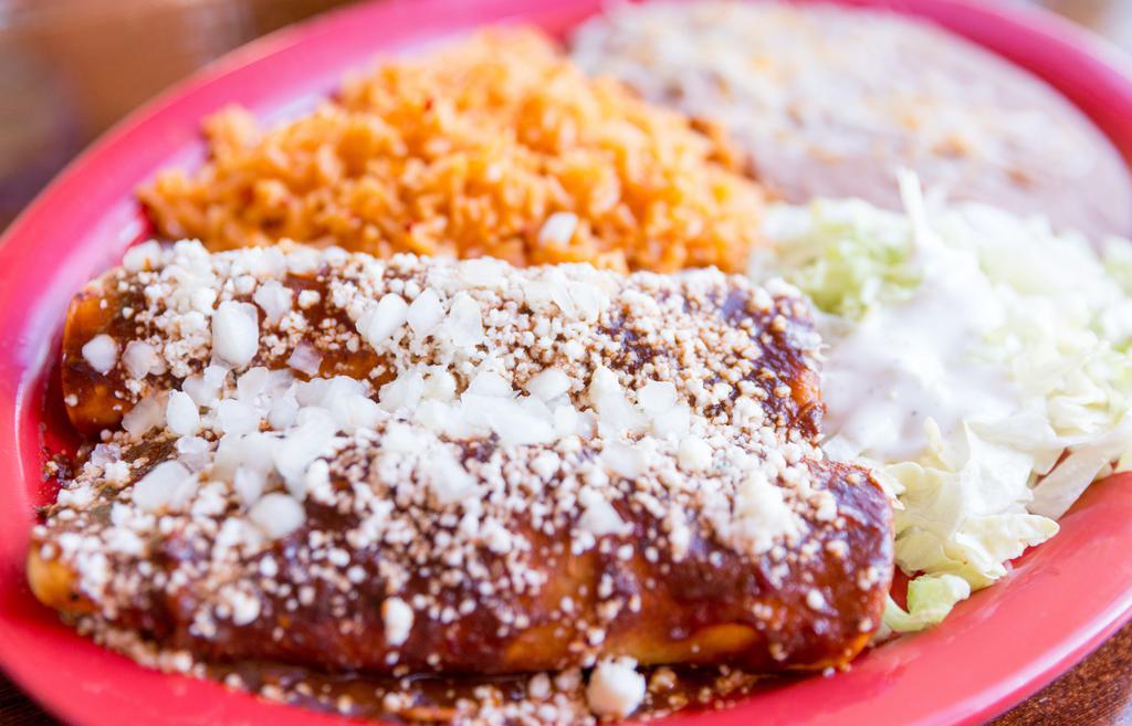 Enchiladas De Mole · Two enchiladas filled with shredded chicken in our famous mole poblano sauce. Topped with even more mole, queso cotija and diced onions. Served with beans and rice.  Contains peanuts.