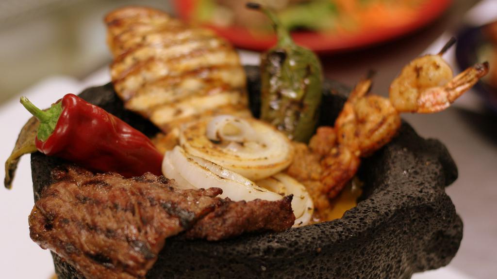 Molcajete Tradicional · Grilled carne arrachera, chicken breast, spicy shrimp, fire-roasted onion, chile burrito and grilled nopales (cactus leaf) in our spicy molcajete salsa with beans, rice and tortillas on the side.
