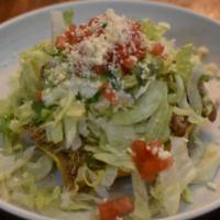 Tostada · Your choice of meat, refried beans, lettuce, tomatoes, queso cotija, Mexican crema and guaca...