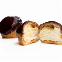 Profiterole Dessert · White cake with dark chocolate mousse and a vanilla cream puff wrapped in a decorated sponge...