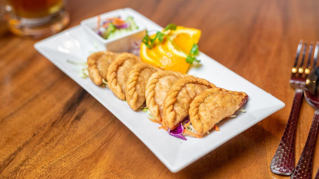 Curry Puff · Taro, yam, potato, onion, stuffed in egg roll shell - deep-fried; served with cucumber salad.