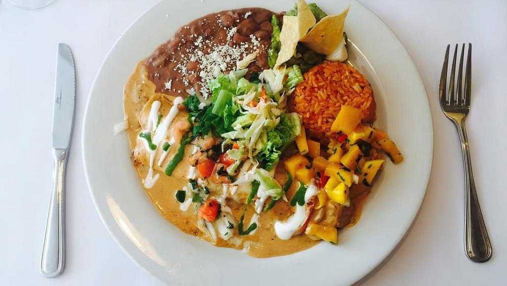 Enchiladas De Mariscos · Grilled seafood marinated in adobo sauce, wrapped in a flour tortilla with a chipotle tequila cream & mango salsa, served with rice & beans.