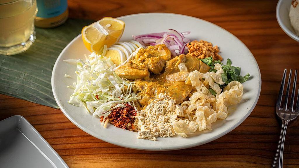 Coconut Chicken Noodles · Flour noodles with coconut chicken curry, roasted chickpea flour, hard-boiled egg, cabbage, wontons, turmeric, chili and fried onions.