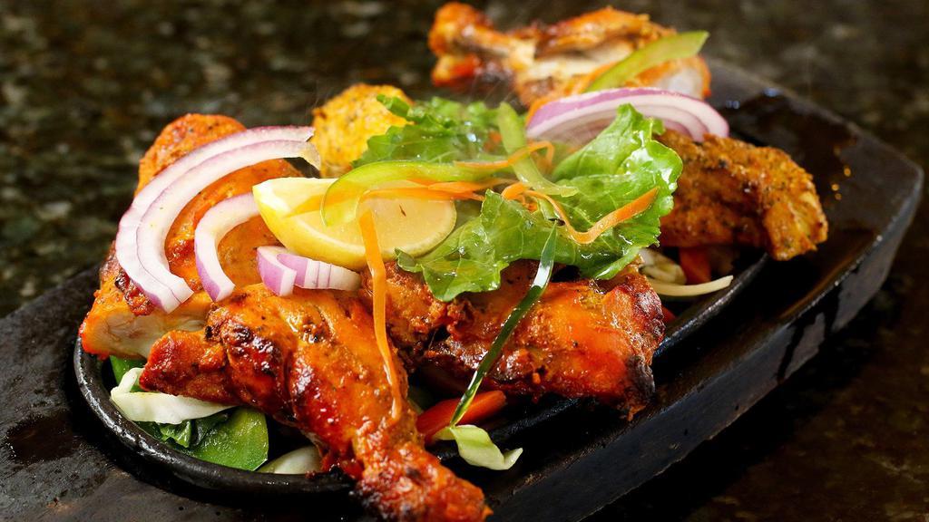 Chicken Tandoori · Chicken Leg Quarter  marinated in yogurt and spices, broiled in the tandoor oven. Served sizzling with sautéed veggies.