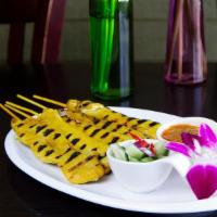 Satay Chicken · Marinated chicken on a skewer served with peanut sauce and cucumber salad.