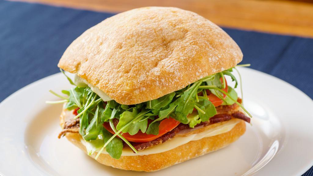 Grilled Turkey Club Sandwich · Sliced turkey breast, bacon, provolone, arugula, thyme aioli, avocado and tomato. Grilled on a ciabatta roll.