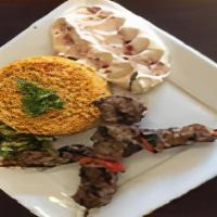 Lamb Kabob Plate · Grilled seasoned Lamb Cubes on a bed of rice with humus , salad and a pita bread