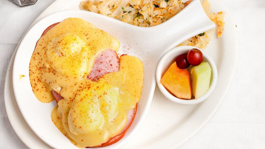 Eggs Benedict · Poached eggs, smoked ham and hollandaise sauce on an English muffin. Served with hash browns and fruit.