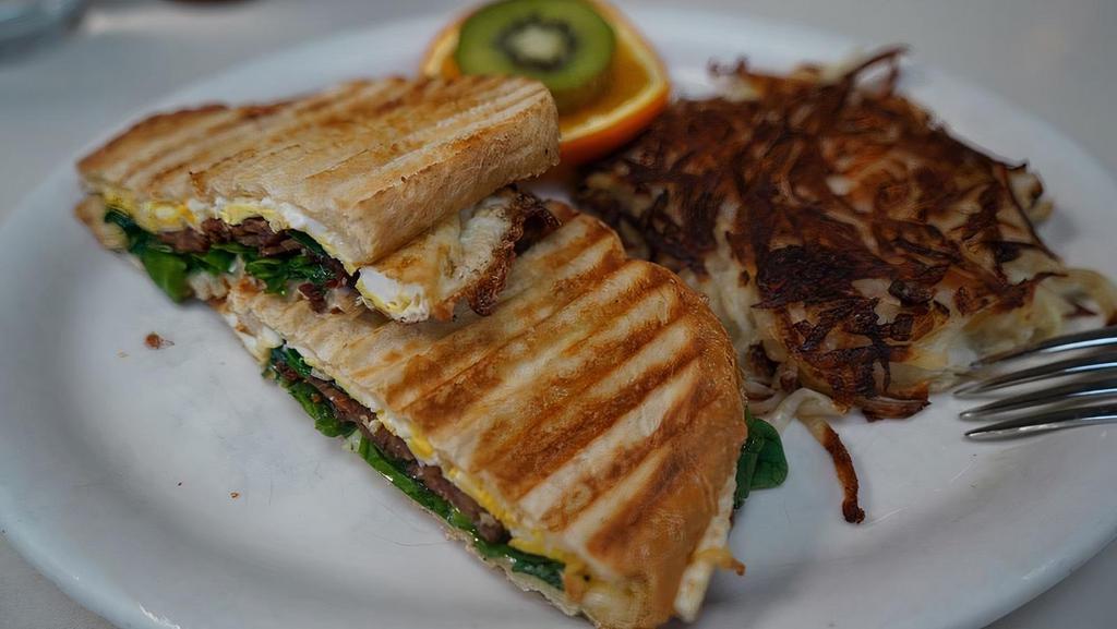Breakfast Panini · Over hard eggs on grilled sourdough with your choice of bacon or thin sliced ham, spinach, and melted swiss cheese, served with home fried red potatoes or hash browns.