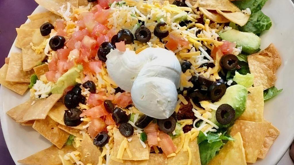 Taco Salad · Chopped romaine lettuce tossed in sweet and sour dressing, cilantro, lime, tomatoes, black beans, avocado, salsa, cheddar-jack cheese and sour cream. Served with tortilla chips and your choice of chorizo or grilled chicken.