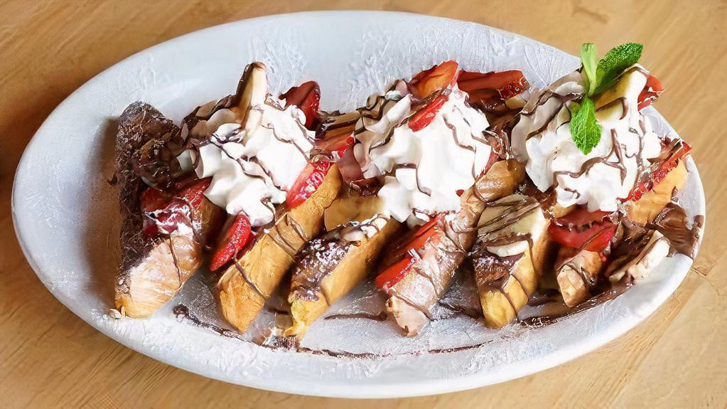 Strawberry Nutella Banana French Toast · 3 thick slices of Texas toast dipped in an egg batter with vanilla, cream, and cinnamon. Topped with Nutella® , bananas, strawberries, and fresh whipped cream.