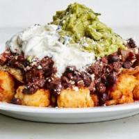 Totaquiles · Customer Favorite! Tater Tots, tossed in chilaquiles sauce with guacamole, black beans eggs,...
