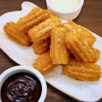 MINI FRESH FRIED CHURROS · Hand piped churros tossed in cinnamon and sugar, served with citrus vanilla cream and chocol...