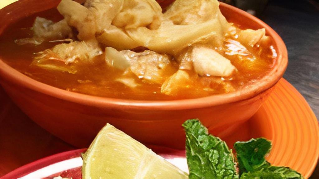 Menudo · Beef tripe soup with side of chopped onions, green pepper and lime.