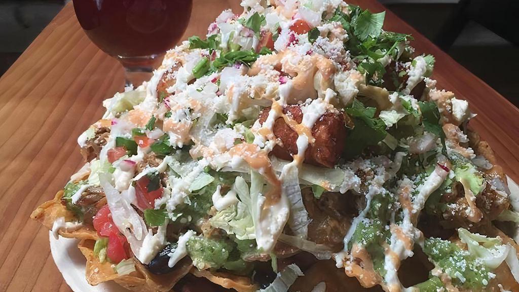 Nacho Macho · Crispy tortilla chips topped with pinto beans, Oaxaca/jack cheese, choice of meat, tomatillo salsa, shredded lettuce, pico de gallo, sour cream, chipotle sauce, and cotija cheese.