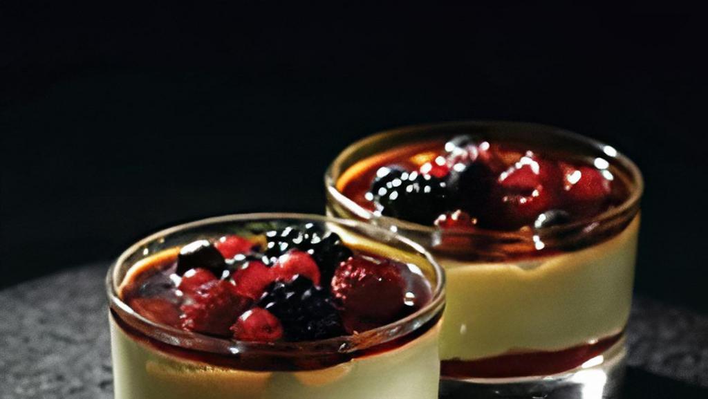 Creme Brulee e Frutti di Bosco · A layer of raspberry sauce topped with a creamy custard and decorated with mixed berries coated in caramel.