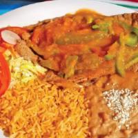Bistec Salvadoreño · Steak cooked in mild tomato sauce topped bell peppers. Served with rice, beans, and salad.